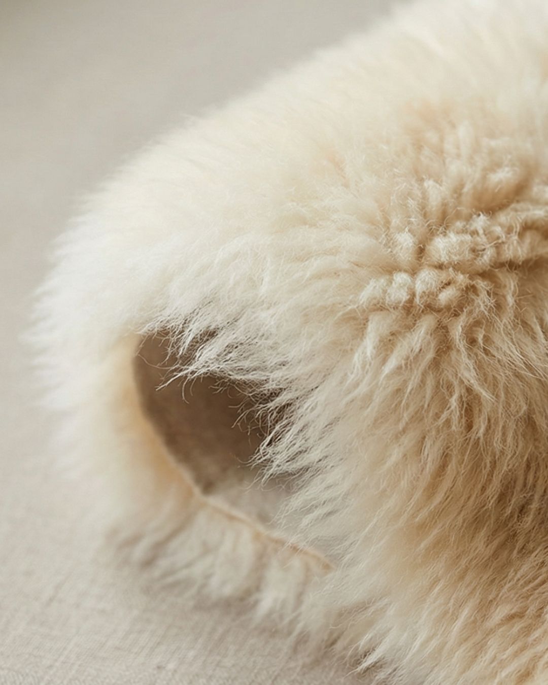 Nahaufnahme von weichem, cremefarbenem Lammfell mit natürlicher Wolle
