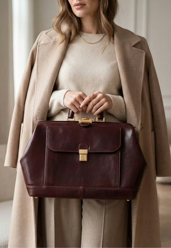 Bordeaux leather doctor’s bag worn casually in front by a woman.