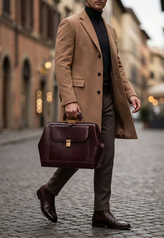 Bordeaux leather doctor’s bag carried in hand by a man on the street.
