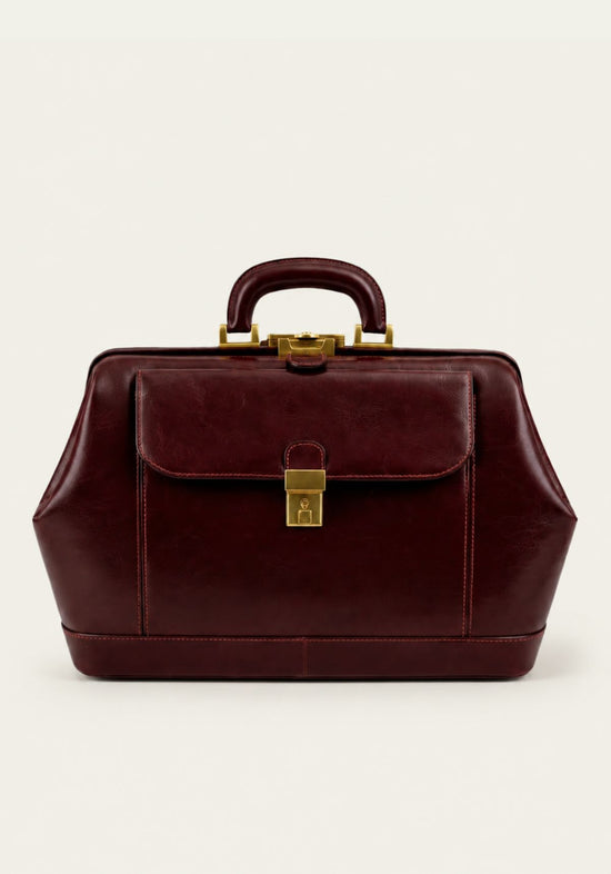 Bordeaux leather doctor’s bag with front flap, lock and handle in front view.
