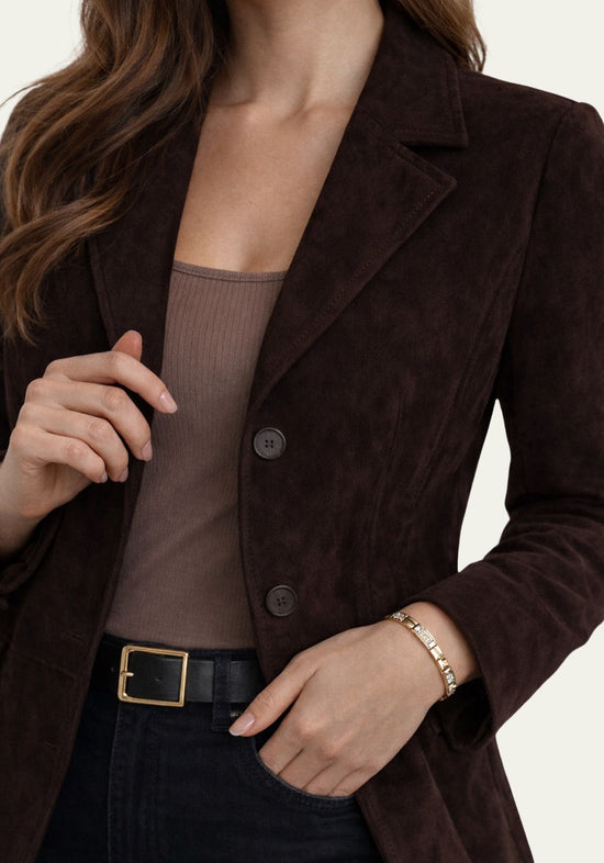 Women's blazer in suede, dark brown, shown in a close detail view on the upper body with buttons and lapels.