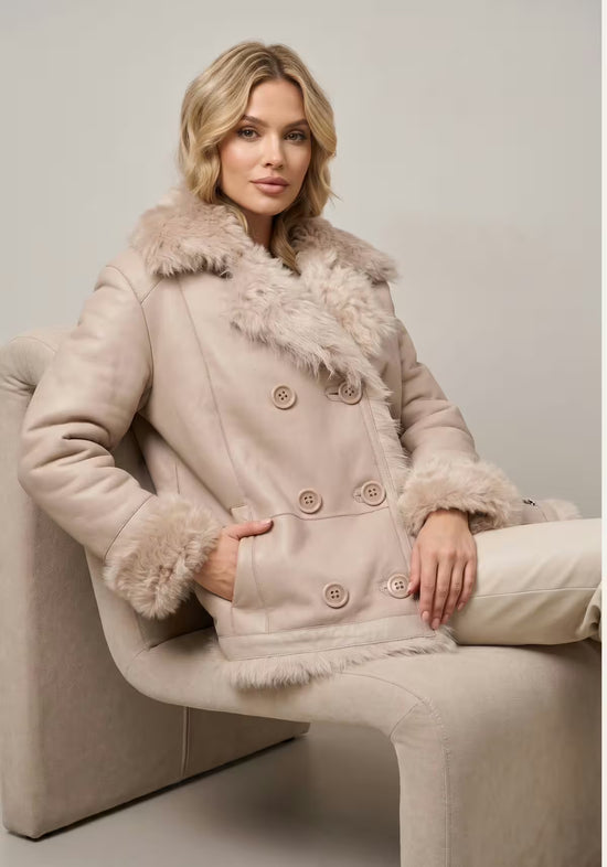 Beige reversible curly sheepskin jacket worn with the smooth leather side and fur trim.