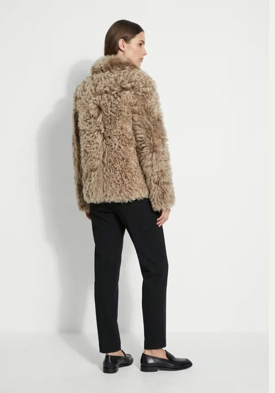 Women’s curly sheepskin jacket in cappuccino, shown from the back with a voluminous woolly texture.