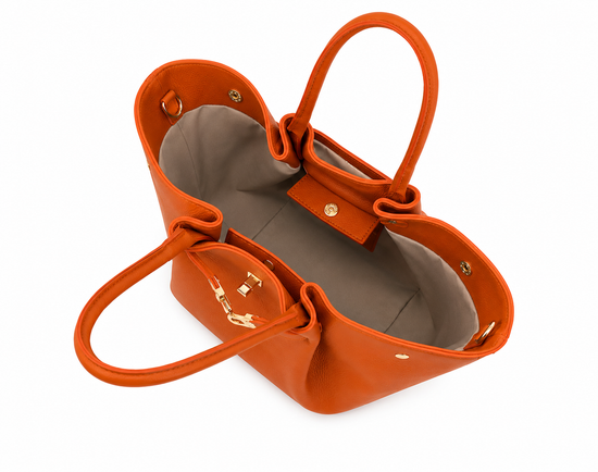 Women's leather handbag in cognac seen from above, with grey lining and an open main compartment.
