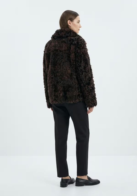 Women's curly sheepskin jacket in dark brown, worn on the model from the back.