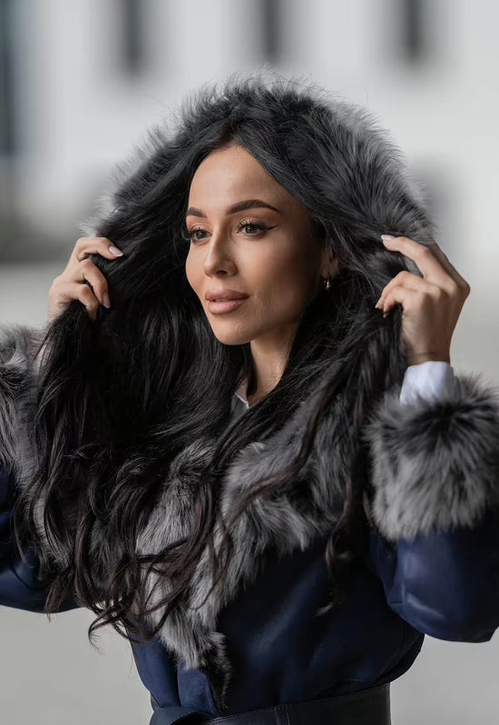 Women's sheepskin coat in dark blue with hood, worn from the front in a close-up