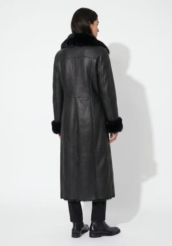 Rear view of a black women’s sheepskin coat with a straight cut and fur collar
