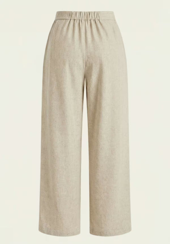 Beige women’s linen trousers shown from the back with an elasticated waist and wide cut.