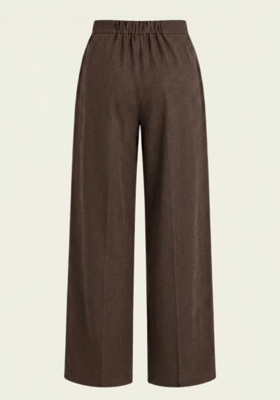 Brown women's linen trousers, shown from the back, with elasticated waistband and wide cut.