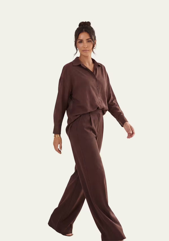 Women’s linen set in brown, worn on a model with a loose fit and long shirt.