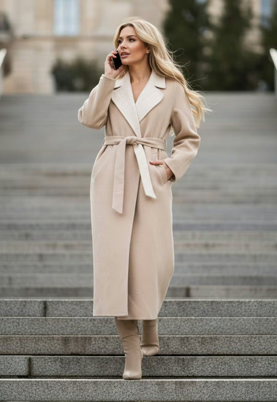 Beige women's wool coat with tie belt and light lapels, shown in a walking view on steps.