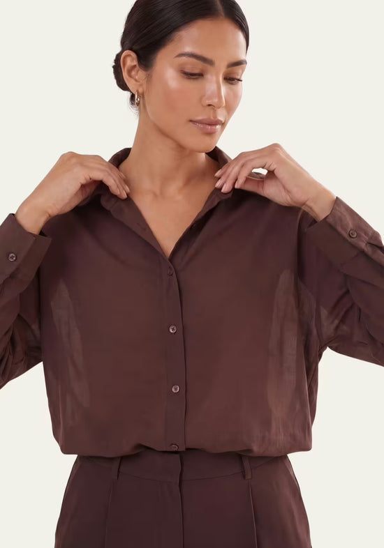 Close-up of the brown women’s linen shirt with collar, buttons and set-in sleeves.
