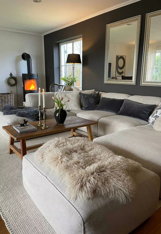 Beige sheepskin decorative rug on the ottoman in the living room, shown in a wide view.