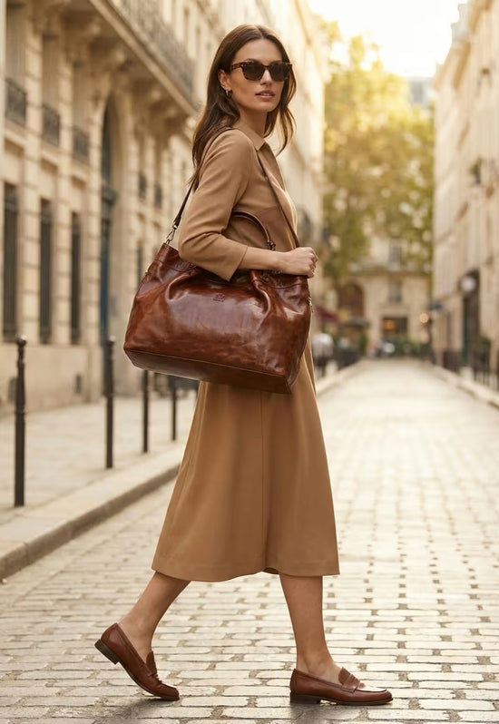Brown leather handbag worn as a shoulder bag during a walk in the city.