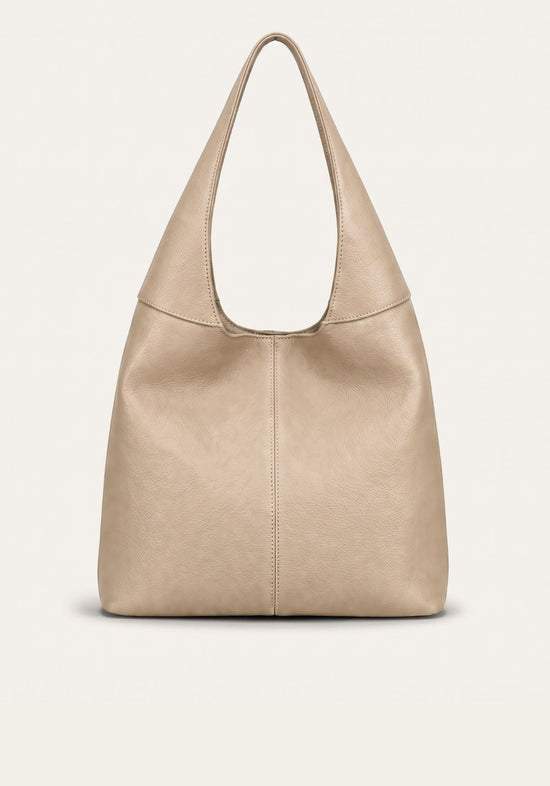 Cream-beige women's leather handbag shown freestanding from the front with a wide shoulder strap.