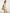 Cream-beige leather hobo bag worn on the shoulder, shown in side view on the model.