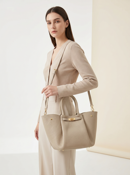 Women's leather handbag in cream beige, shown from the side while worn with the long shoulder strap.