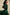 Black women’s leather handbag worn over the shoulder with a green dress