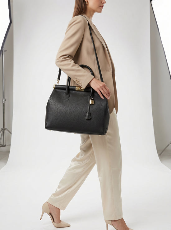 Black ladies' leather handbag worn crossbody by a woman walking
