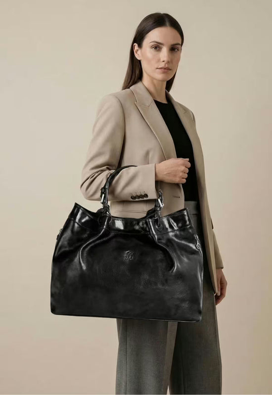 Black leather handbag as a large shoulder bag, worn by a woman in side view.