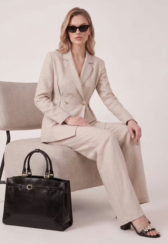 Black women's leather handbag placed beside a seated woman in a light studio