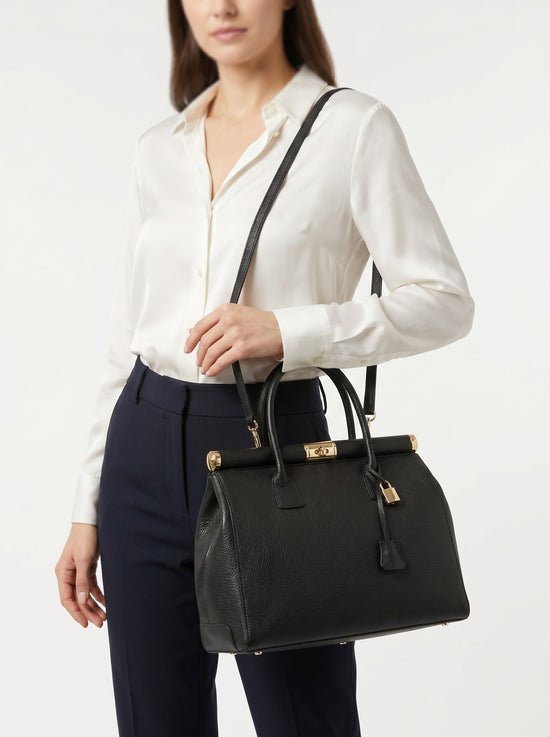 Black ladies' leather handbag worn by a woman as a shoulder bag
