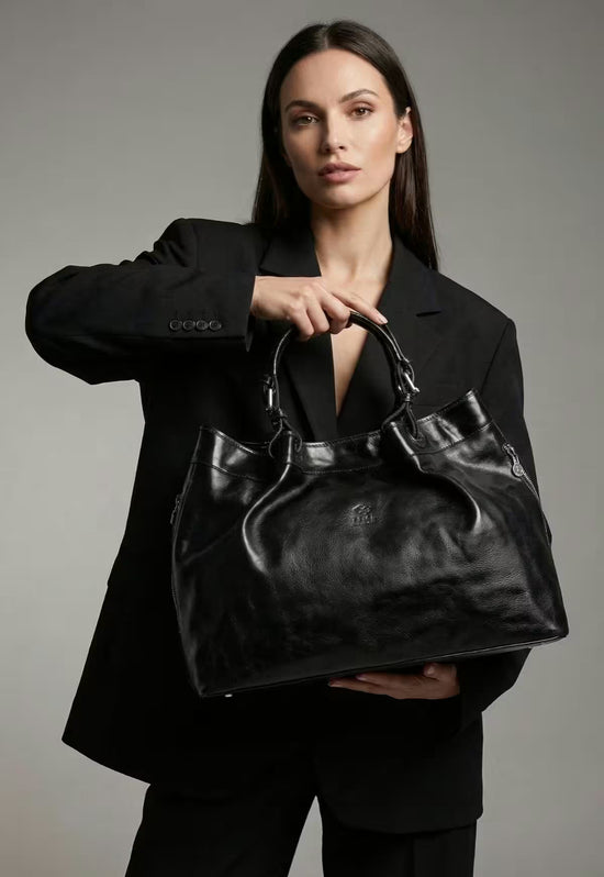 Black leather handbag for women, carried by a model against a dark background.