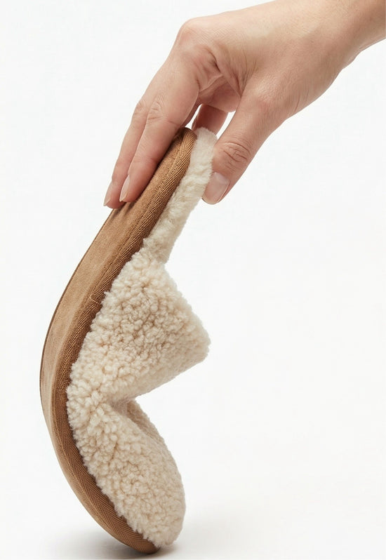 Women's sheepskin slipper in natural tone, bent by hand with the flexible sole visible