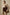 Brown leather hobo bag is worn by a woman as a shoulder bag with a beige suit.
