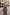 Brown leather hobo bag is worn crossbody over the shoulder in a city street scene.