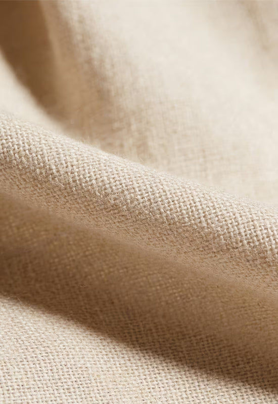 Close-up of the beige linen fabric on the men's trousers with a clearly visible weave texture.