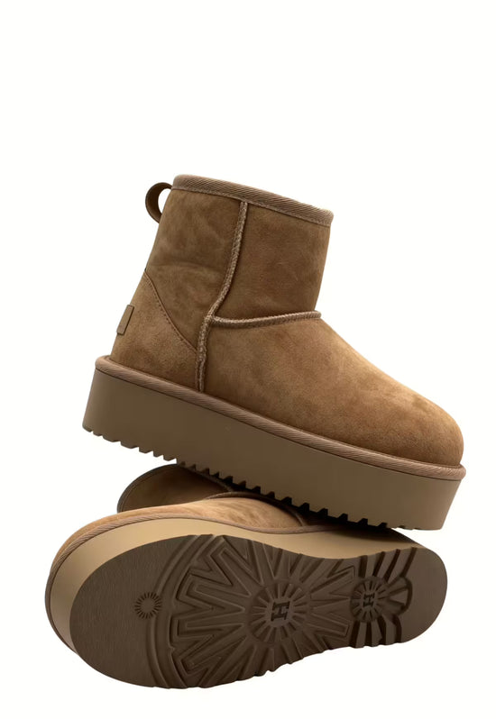 Brown sheepskin ankle boot in side view with the treaded sole shown in detail.