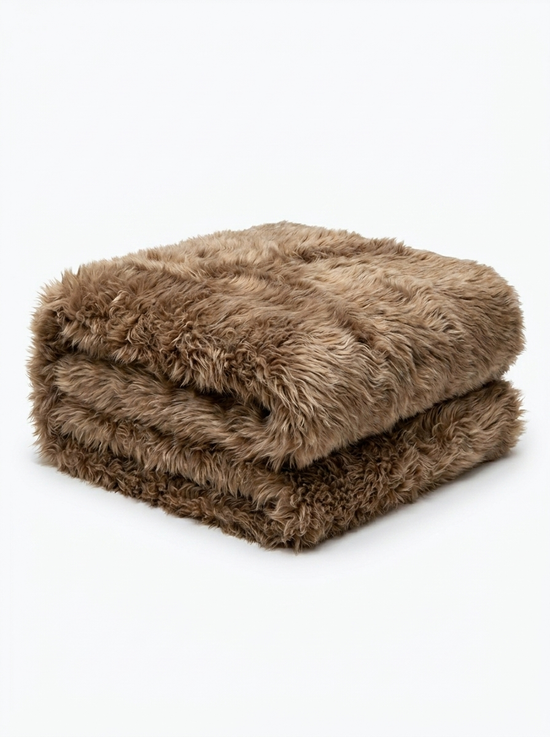 Folded sheepskin blanket made from curly sheepskin in cappuccino on a white background.