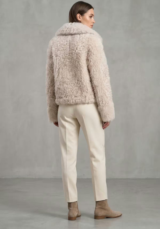 Curly sheepskin jacket for women in cream beige, shown from the back as worn, with a short cut and soft fleece.