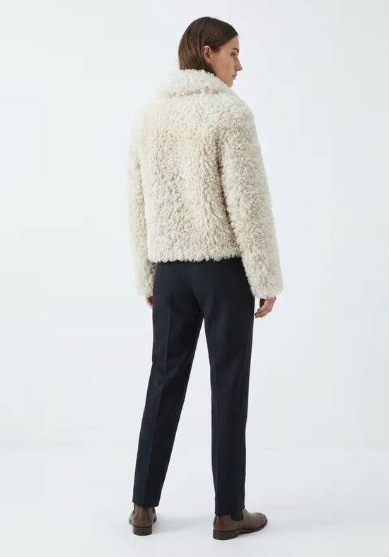 Cream curly sheepskin jacket for women shown from the back with a short cut and fluffy texture
