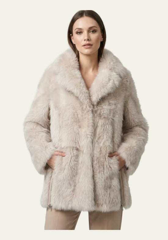 Women’s sheepskin jacket in cream-beige worn on a model from the front, with wide collar and pockets.