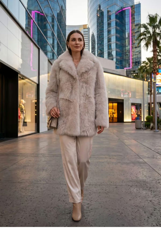Cream-beige women’s sheepskin jacket worn while walking on the street, shown from the front.