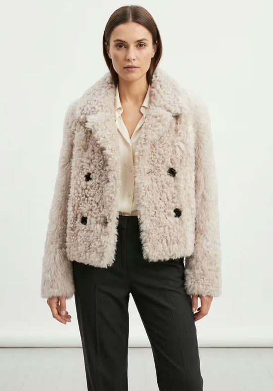 Women’s curly sheepskin jacket in cream beige, worn open on a model from the front.