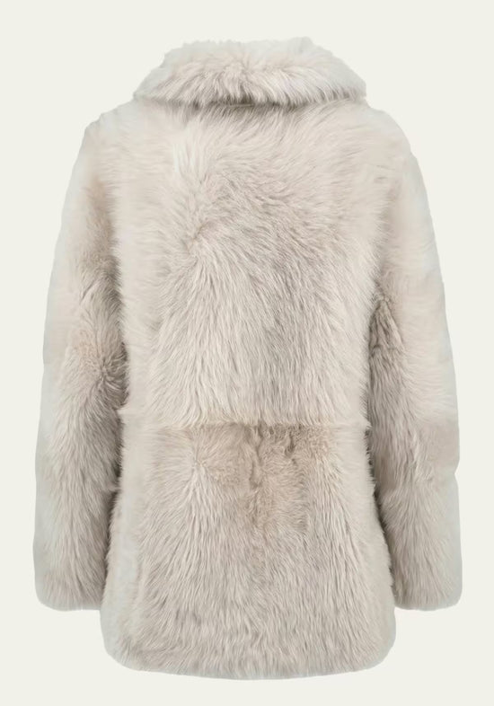 Freestanding back view of the cream-beige women’s sheepskin jacket with fluffy fur and collar.