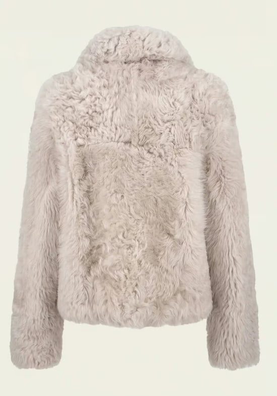 Back view of the women’s curly sheepskin jacket in cream beige with textured fur.