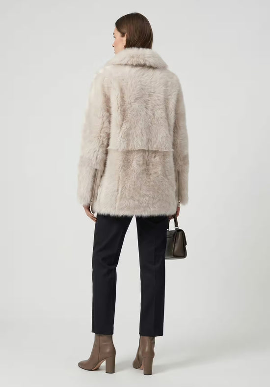 Cream-beige sheepskin jacket for women on a model in back view, with a hip-length cut.