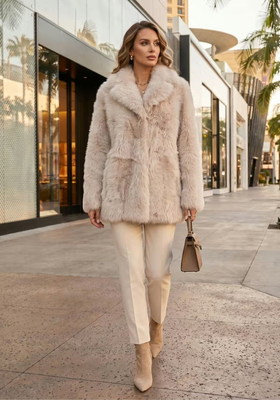Women’s cream-beige sheepskin jacket shown in an outdoor look with trousers, ankle boots and handbag.