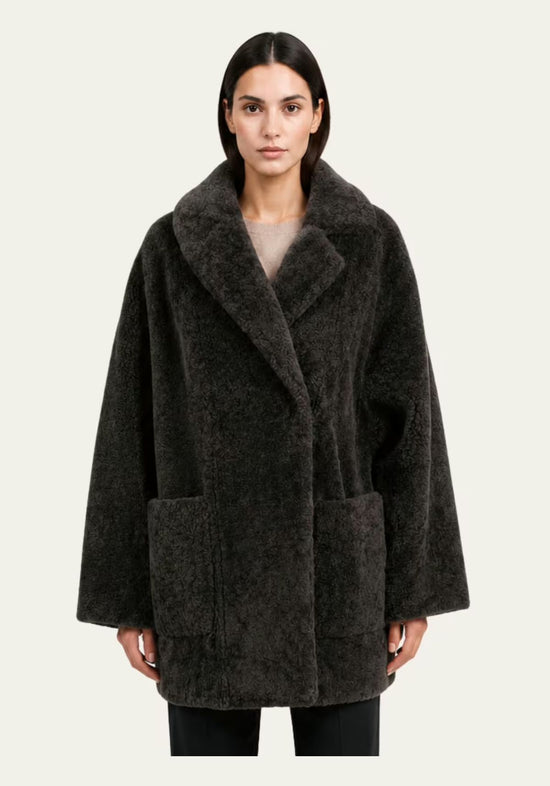 Women’s sheepskin jacket in khaki worn on model, front view with wide lapels and large pockets.