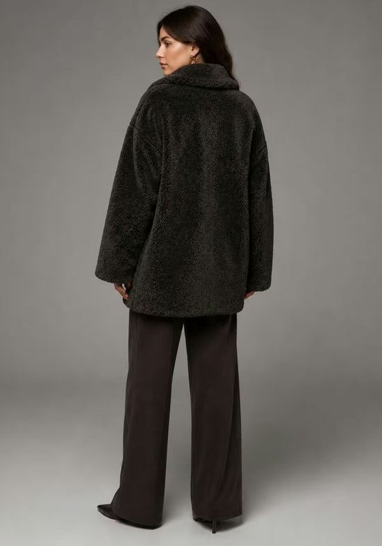 Women’s sheepskin jacket in khaki from the back against a grey background, with a smooth back and relaxed shape.