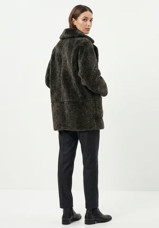 Women’s sheepskin jacket in khaki on model, back view with a straight cut and wide collar.