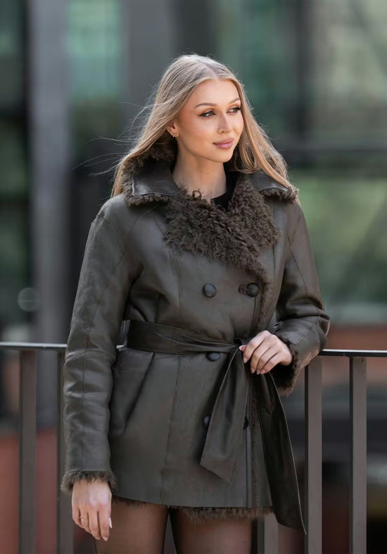 Women’s sheepskin jacket in olive with smooth leather outer side, belt and shearling trim at the collar.