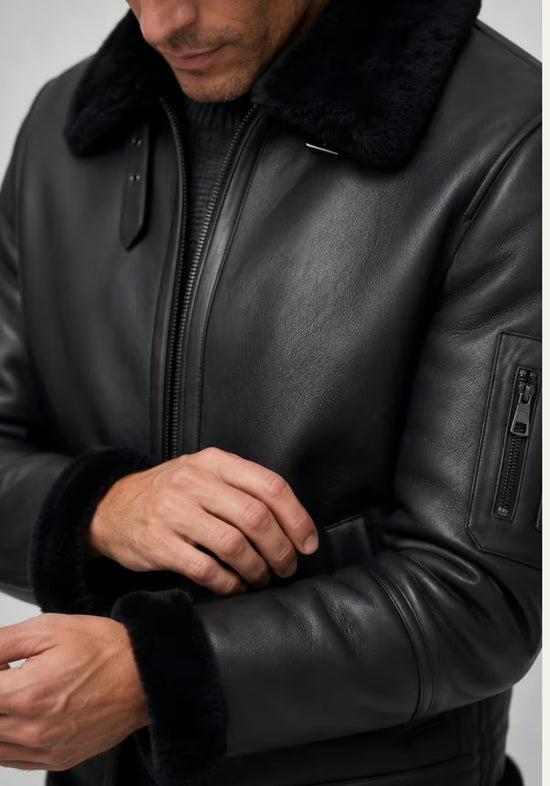 Detail of the black men's sheepskin jacket with sleeve, zip pocket and shearling trim.