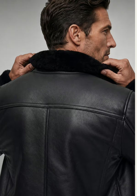 Rear view on the model with the collar raised on the black men's sheepskin jacket.