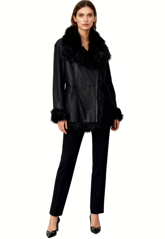 Black sheepskin jacket for women, worn on the model with a wide collar and slim trousers.