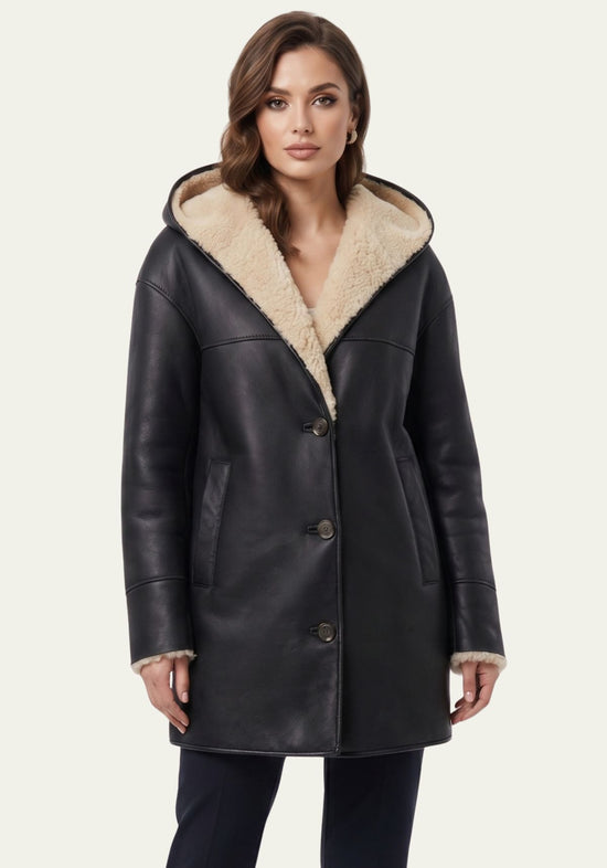 Black women’s sheepskin jacket with hood in a front view, lined with light sheepskin and worn closed.